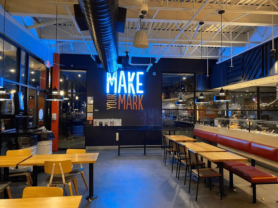 Restaurant dining room with pendant lights over the tables and a neon sign on the wall