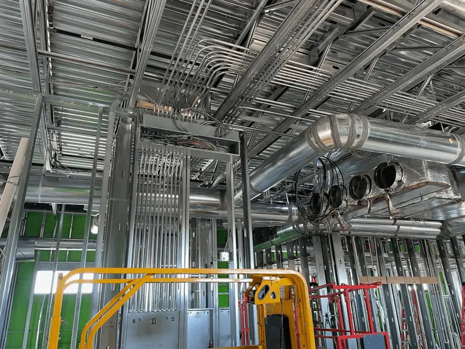 Commercial rough-in: conduit runs through steel-stud framing beside a scissor lift