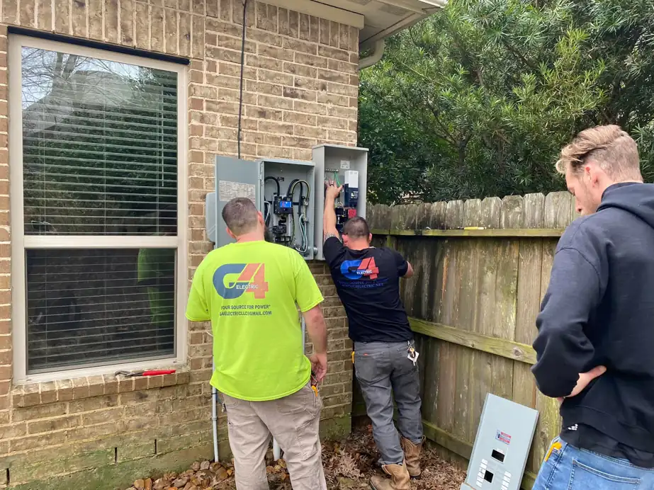 Two G4 Electric electricians working at a meter base and panel on a brick home