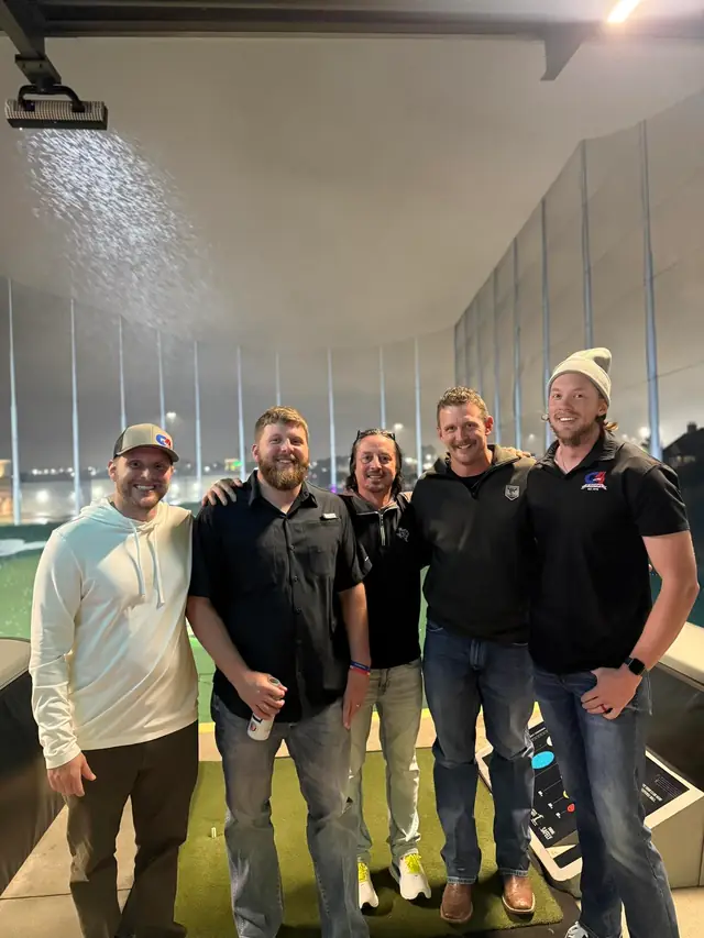 Five men posing at a driving range bay, two of them wearing G4 Electric polo shirts